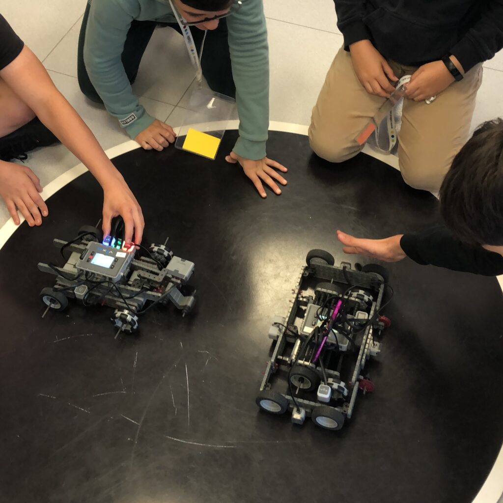 Dos robots VEX IQ enfrontats a la pista de sumo de robots durant una competició de robòtica educativa